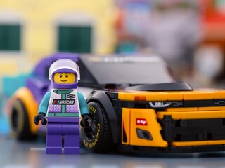 Obraz premium Tambov, Russian Federation - January 02, 2026 Lego NASCAR Next Gen Chevrolet Camaro ZL1 driver minifigure standing near his car in city street. LEGO Speed Champions.