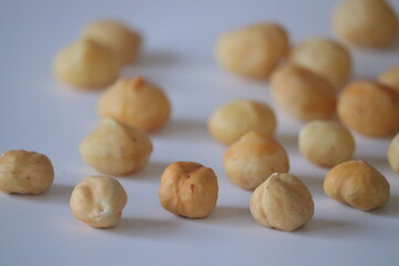Fototapeta premium Roasted macadamia nuts presented in a rustic close-up scatter, featuring whole shelled kernels on parchment