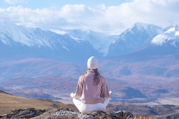 Woman practicing yoga and meditation in autumn mountains surrounded by scenic beauty and peaceful...