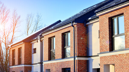 Fototapeta premium Terraced residential homes with modern facade in newly developed housing estate. The real estate market in the suburbs. New terraced houses in a new development area.