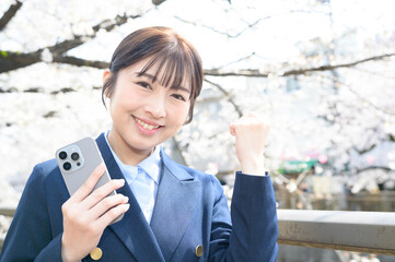 桜を背景にガッツポーズをする日本人女性