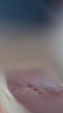 Close-up view of matchstick being struck on matchbox surface, creating flame against blurred background. Vertical format video