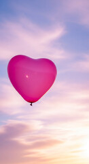 Obraz premium Vertical shot of a pink heart balloon against a blurred, pastel sky, symbolizing love, romance, or Valentine's Day, ideal for celebration content