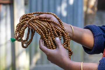 Close-up of female hands holding a large, coiled set of traditional wooden prayer beads for spiritual meditation, religious recitation, and devotion. Concept of faith, prayer, and mindfulness.