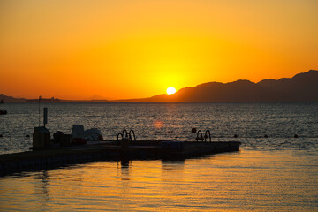 The sun rises over the sea from behind Tiran Island in Egypt.