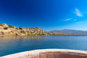 Crystal clear sea and a fortress on a hillside in Molivos (Mithymna) on the Greek island of Lesvos on a sunny day, wallpaper or background for your project