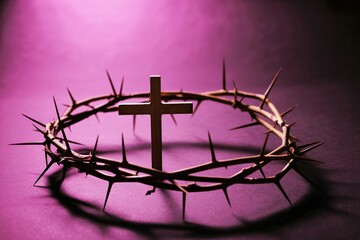 Crown of thorns with a cross symbolizing christian faith and sacrifice on a purple background with dramatic