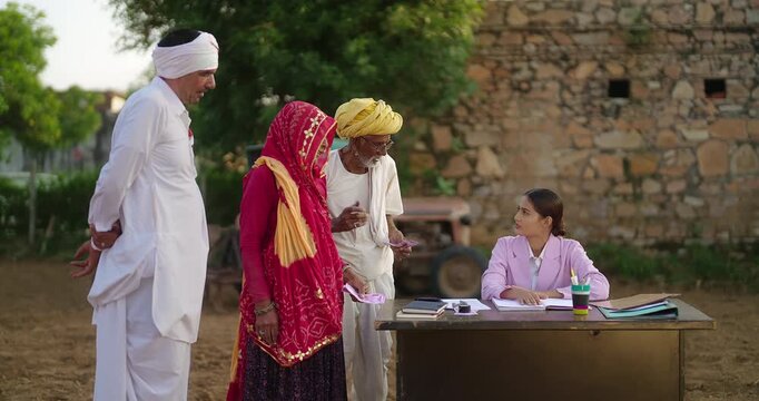 Indian young adult female sitting on chair talk share bank loan ideas to to old aged farmer man woman banker girl do village visit field work older male lady hold cash money at rural area ground place