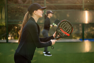 Woman Padel tennis player with racket in action on the court. Girl athlete with paddle racket on...