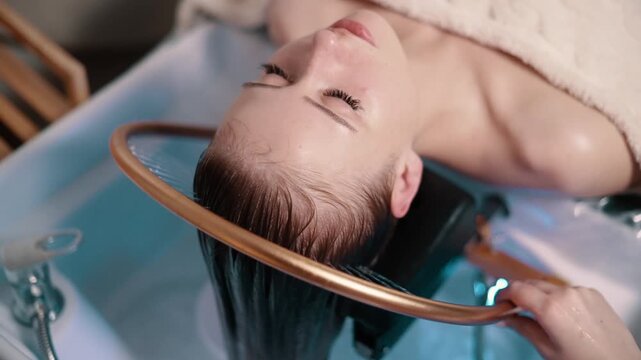 Young woman receiving a head massage during a Japanese head spa treatment with water flowing from a special hair washing tool.