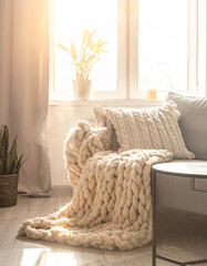Cozy living room interior with chunky knit blanket on a fabric sofa in warm morning light