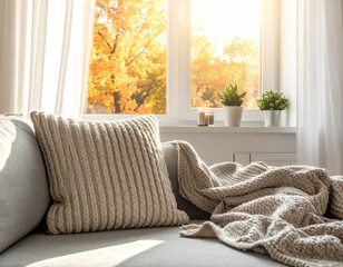 Cozy living room interior with chunky knit blanket on a fabric sofa in warm morning light