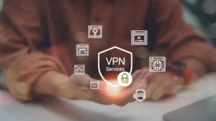 Close up of a man holding a digital shield icon with VPN Services text, representing secure internet connection, data privacy, and cyber protection on a blurred background.