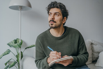 Handsome middle eastern looking man journaling or writing in a notebook