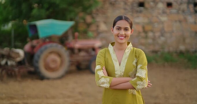 Indian young adult gen z villager female staff fold hand look camera standing visit rural area. Happy proud girl officer cross arm staring cam do casual pose enjoy new day village ground place 