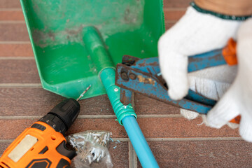 Close-up hand of man use rivet gun or rivet pliers to repair the plastic dustpan. attach rivets with PVC pipe.