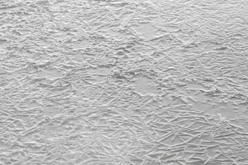 Frozen water crystals on thin ice. Gray background.