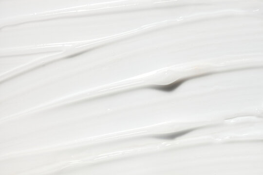 Cosmetic beauty product silky cream texture beige milky white colored background
