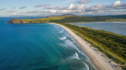 Aerial perspective of a narrow coastal isthmus with a sandy beach and a calm lagoon.