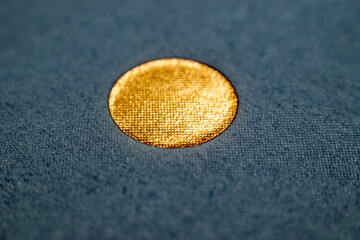 Macro of Golden Textured Circle on Blue Fabric