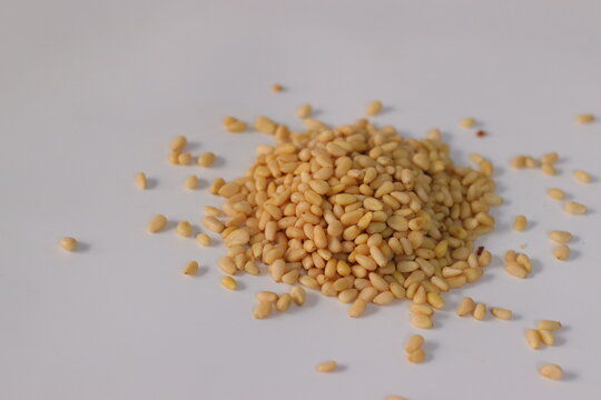 Pine nuts, also known as pine kernels, presented in a loose pile, featuring shelled seeds on a clean surface. Close-up food image highlighting smooth texture, commonly used in Mediterranean cuisine