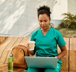 Young woman or a nurse or a doctor during office hours break enjoying sunny day while using laptop...