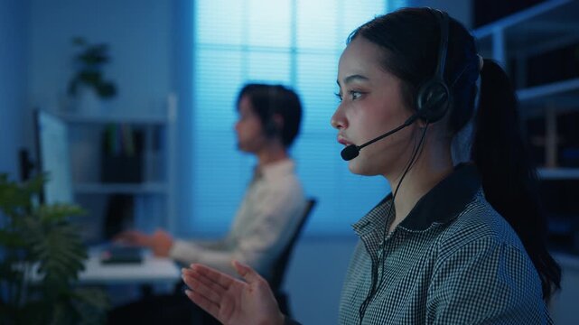Closeup Gen z Asia young call center team or customer support service executive use computer and microphone headset work technical e commerce in late night office. Telemarketing or sales job concept.