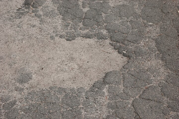 Old cracked gray asphalt surface conveying abandonment and neglect.