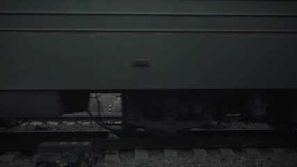 Freight locomotive powers train as it moves along the railway tracks laid on wooden sleepers, transporting goods during a gloomy autumn period, capturing the essence of railway transport and movement