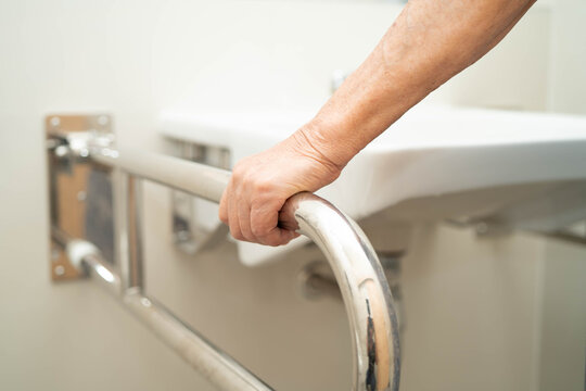 Asian elderly woman use safety handrail in bathroom.