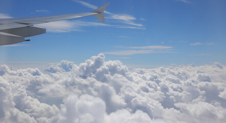 Obraz premium white clouds at 40000 feet altitude from the airplane seeing a piece of the wing