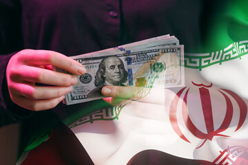 Hands holding US dollars in front of Iranian flag showing financial trade between countries