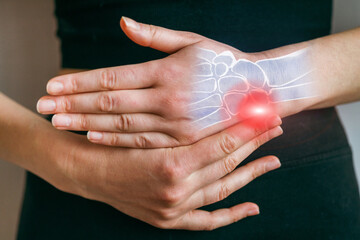 Hand holding wrist showing pain with bones highlighted in a medical setting near a light background