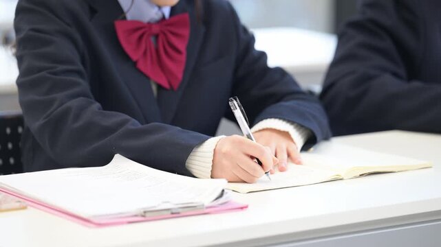 高校生が学校の教室や塾の授業で勉強をするノートを書くシーンの手元のクローズアップ動画　顔無し