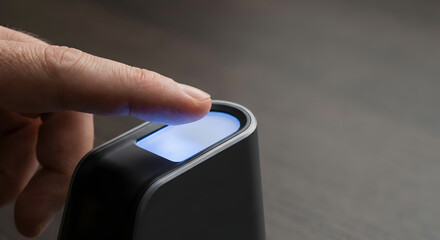 Close-up of finger scanning on illuminated biometric security device.