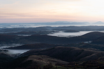 Gradina viewpoint at mountain Zlatibor offering beautiful view of hilly rural landscape and valleys filled with fog at dawn, visit Serbia countryside, autumn season at October