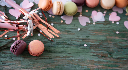 Birthday celebration with delicious macarons surrounded by pink confetti hearts on green shabby...