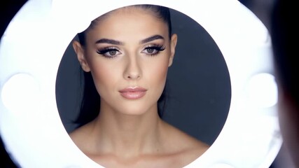 Beautiful young European woman posing with professional makeup and ring light illumination for beauty portrait session