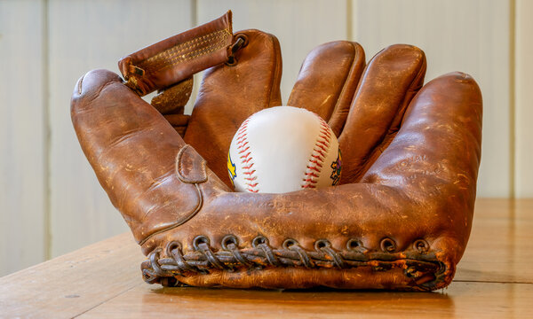 Closeup of vintage 1940s baseball glove, with baseball, on a tabletop 