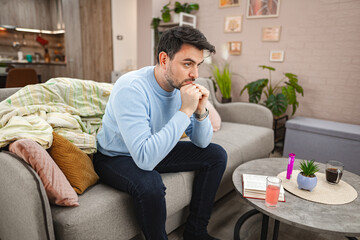 Fototapeta premium Depressed man sitting thoughtfully on couch