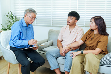 Obraz premium Senior asian male psychiatrist writing notes while listening couple during therapy session representing communication trust emotional healing process in professional counseling room for mental health