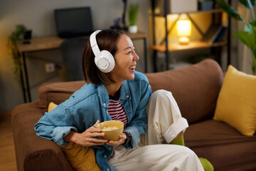 Cheerful woman relaxing on couch and listening to music at home