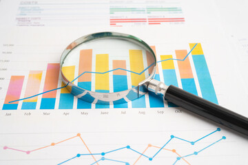 Magnifying glass on charts graphs paper.