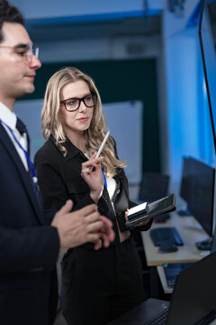 A diverse and dedicated team of professionals works diligently in a bustling, modern tech office at night, collaborating and focusing on their tasks to meet a critical project deadline.