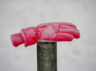 Vereister roter Kinderhandschuh auf Pfahl