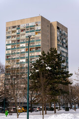Building with balconies near snow-covered trees in a winter city scene during the day