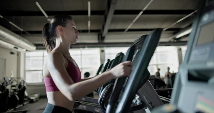 Young beautiful woman in sportswear doing cardio workout and exercises on stepper machine in the gym