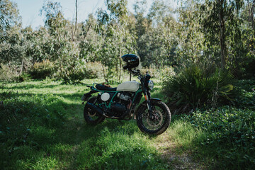 Fototapeta premium Hombre aventurero con barba en moto estilo scrambler en el bosque en dia soleado