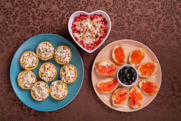 Chicken salad. Salad in tartlets. Canapes with red caviar, trout, and olives on a plate