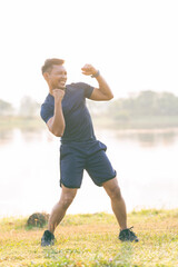 A young man in a T-shirt and shorts is stretching, with the sunlight shining in the background, creating a pre-workout training atmosphere.
